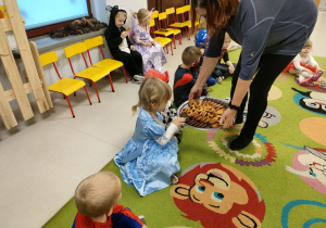 Ciocia Bożenka częstuje dzieci słodkimi przekąskami.