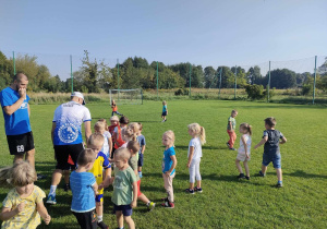Dzieci z grupy "Pszczółek" podczas zabawy ruchowej na boisku sportowym.