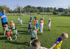 Dzieci z grupy "Pszczółek" podczas zabawy ruchowej na boisku sportowym.