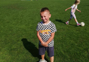 Natan ze "Skrzatów" z piłką na boisku sportowym.