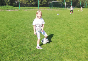Maja ze "Skrzatów" z piłką na boisku sportowym.