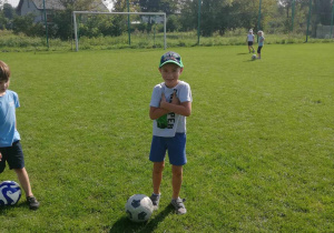 Antoś ze "Skrzatów" z piłką na boisku sportowym.