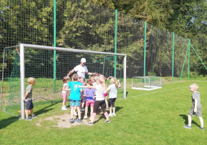 Dzieci z grupy "Skrzatów" w trakcie zabawy ruchowej na boisku sportowym.