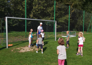 Dzieci z grupy "Skrzatów" w trakcie zabawy ruchowej na boisku sportowym.