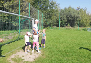 Dzieci z grupy "Skrzatów" w trakcie zabawy ruchowej na boisku sportowym.