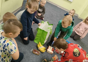 Chłopcy z grupy "Pszczółek" rozpakowują "eko-torbę" z ekologicznymi owocami.