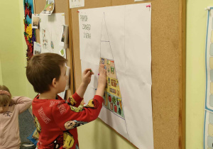 Kajtek przyczepia ilustrację produktów mlecznych na właściwym miejscu na piramidzie zdrowego żywienia.