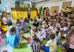 Pani prowadząca zaprasza przedszkolaki do udziału w spektaklu teatralnym.