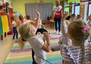 Dzieci biorą udział w zabawach ruchowych proponowanych przez trenera.