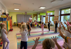 Dzieci biorą udział w zabawach ruchowych proponowanych przez trenera.