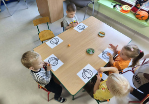 Maluszki wyklejają szablon dyni z użyciem plasteliny.