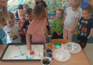 Dzieci z "Pszczółek" tworzą swój wspólny obraz malowany na mleku.