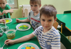 Dzieci ze "Skrzatów" prezentują swoje obrazy malowane na mleku.