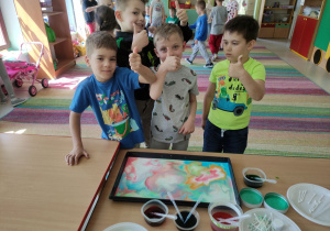 Dzieci z "Kaczuszek" prezentują swój obraz malowany na mleku.