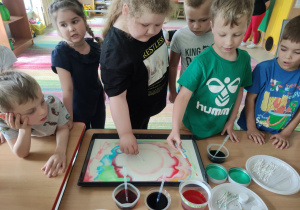Dzieci z "Kaczuszek" tworzą swój wspólny obraz malowany na mleku.