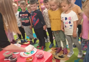Dzieci z "Biedronek" oglądają w jaki sposób należy malować barwnikami na mleku.