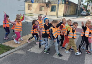 Dzieci z Grupy Skrzaty przechodzą przez przejście dla pieszych.