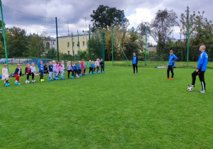 Dzieci z grupy "Skrzaty" słuchają trenera-p. Mateusza Maciejewskiego.