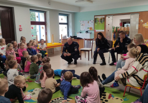 Dzieci uważnie słuchają podczas spotkania z funkcjonariuszami policji.