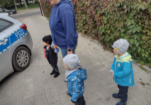 Maluszki wraz z ciocią Krzysią oglądają samochód policyjny.