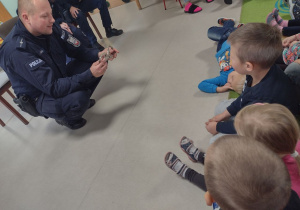 Pan Policjant prezentuje przedszkolakom specjalistyczny sprzęt.