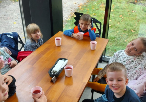 dzieci z grupy "Kaczuszki" siedzą przy stoliku i czekają na obiad