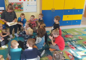 Babcia jednego z przedszkolaków czyta bajkę dzieciom z grupy "Skrzaty".