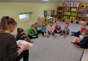 Babcia jednego z przedszkolaków czyta bajkę dzieciom z grupy "Biedronki".