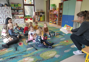 Babcia jednego z przedszkolaków czyta bajkę dzieciom z grupy "Motylki".