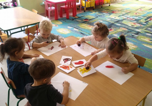 Kilkoro dzieci z grupy "Motylków" przy stoliku w trakcie malowania kasztanem.