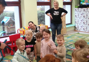 Kilkoro dzieci z grupy "Motylków" z ciocią Krzysią i Karoliną wraz z psem należącym do strażaków.