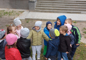 Dzieci z grupy "Skrzatów" bawią się na ogrodzie przedszkolnym w zabawę o nazwie "Krowa".
