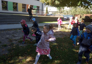 Dzieci z grupy "Kaczuszek" bawią się na ogrodzie przedszkolnym w "Raz, dwa, trzy, Baba Jaga patrzy".
