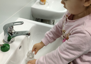 Dziewczynka z "Motylków" wymienia wodę w poidełku chomika.