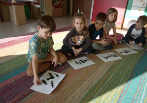 "Czerwony Kapturek" w "Kaczuszkach"-kilkoro dzieci podczas słuchania bajki z jednoczesnym nakładaniem ilustracji postaci występującej w bajce.