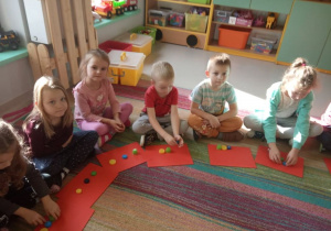"Trzy świnki" w "Kaczuszkach"-kilkoro dzieci podczas aktywnego słuchania bajki ilustruje treść tej bajki za pomocą kolorowych nakrętek-świnek.