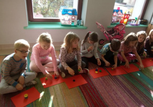 "Trzy świnki" w "Kaczuszkach"-kilkoro dzieci podczas aktywnego słuchania bajki ilustruje treść tej bajki za pomocą kolorowych nakrętek-świnek.