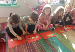 "Trzy świnki" w "Kaczuszkach"-kilkoro dzieci podczas aktywnego słuchania bajki ilustruje treść tej bajki za pomocą kolorowych nakrętek-świnek i ilustracji domków.