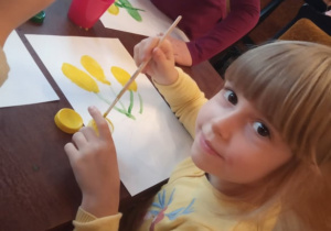 Dziewczynka z "Kaczuszek" maluje swój obraz.