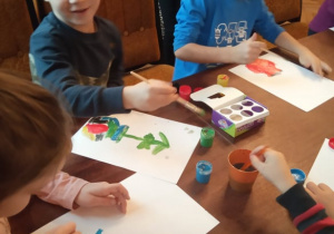 Troje dzieci z "Kaczuszek" maluje swój obraz.