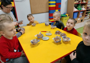 Kilkoro dzieci z grupy "Pszczółek" przy stole podczas ozdabiania bombek.