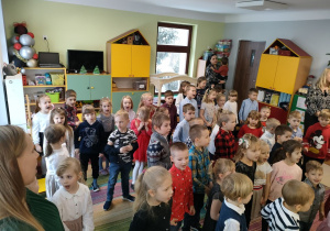 Dzieci stoją na dywanie i śpiewają/słuchają kolędy.