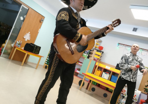 "Mariachi" w typowym stroju gra na instrumencie.