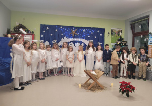 Dzieci z grupy "Kaczuszek" w trakcie występów na Uroczystości Choinkowej. W tle jest dekoracja świąteczna.