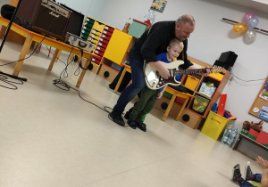 Tymon przy pomocy p. Bogdana, gra na gitarze elektrycznej.