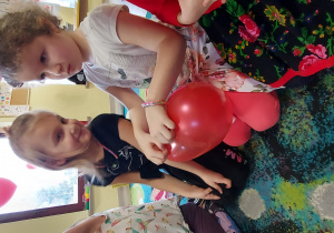 Dwie dziewczynki z grupy " Skrzaty" trzymają balon w kształcie serca podczas zabawy w kole.