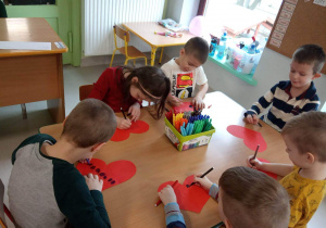Killkoro dzieci z grupy Kaczuszek przy stoliku w trakcie ozdabiania walentynkowego serca.