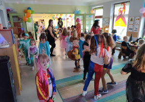 Przedszkolaki wraz z ciociami tańczą na balu karnawałowym.