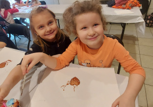 Dwie dziewczynki z grupy "Skrzaty" pozują do zdjęcia podczas malowania gipsowego serduszka.