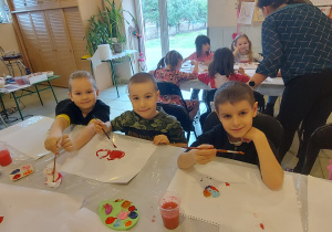 Trzech chłopców z grupy "Skrzaty" pozuje do zdjęcia podczas malowania gipsowego serduszka.
